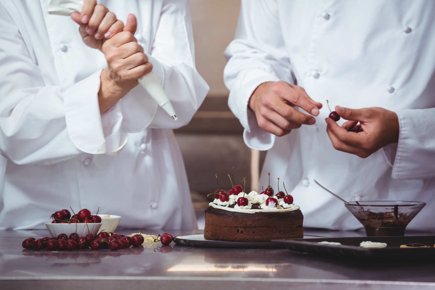 Pastry chefs finishing a cherry-topped chocolate cake